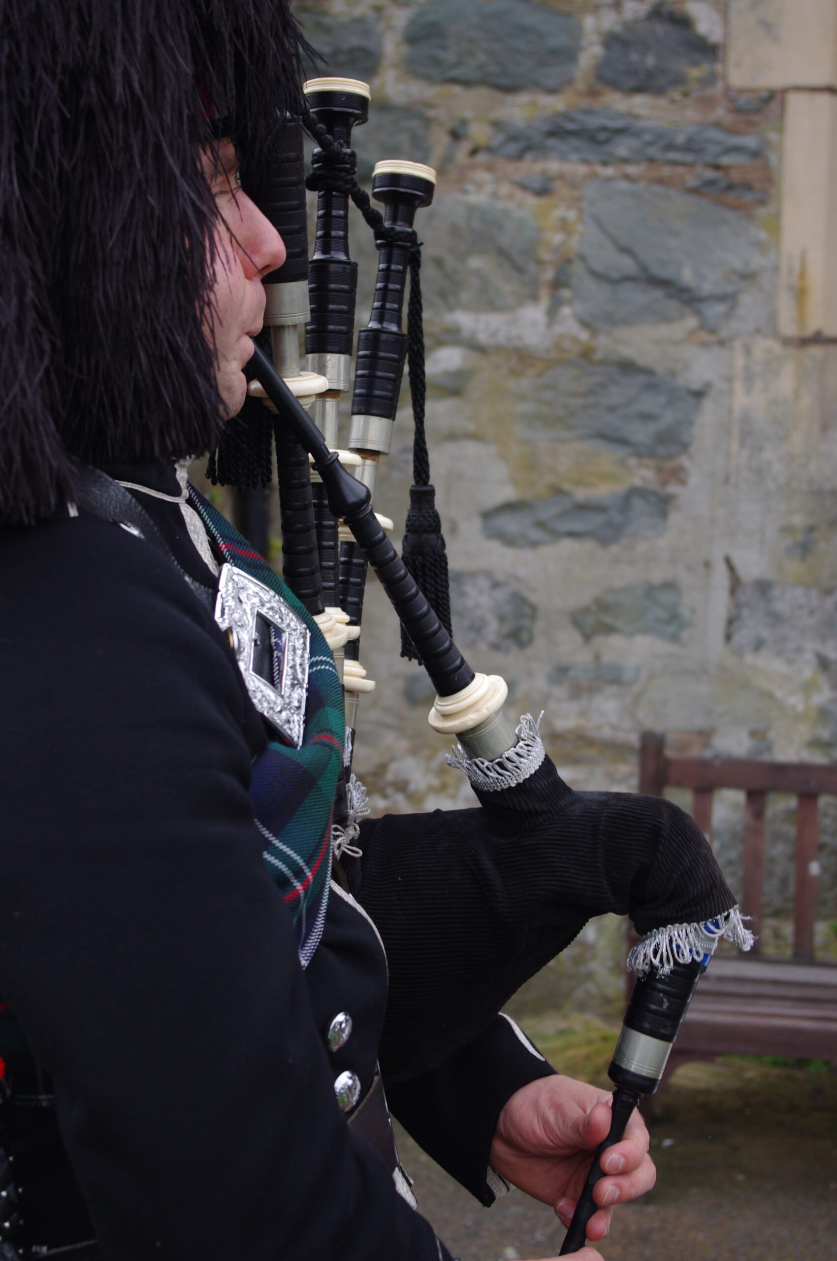An image of a bagpiper in traditional highland garments playing his bagpipes