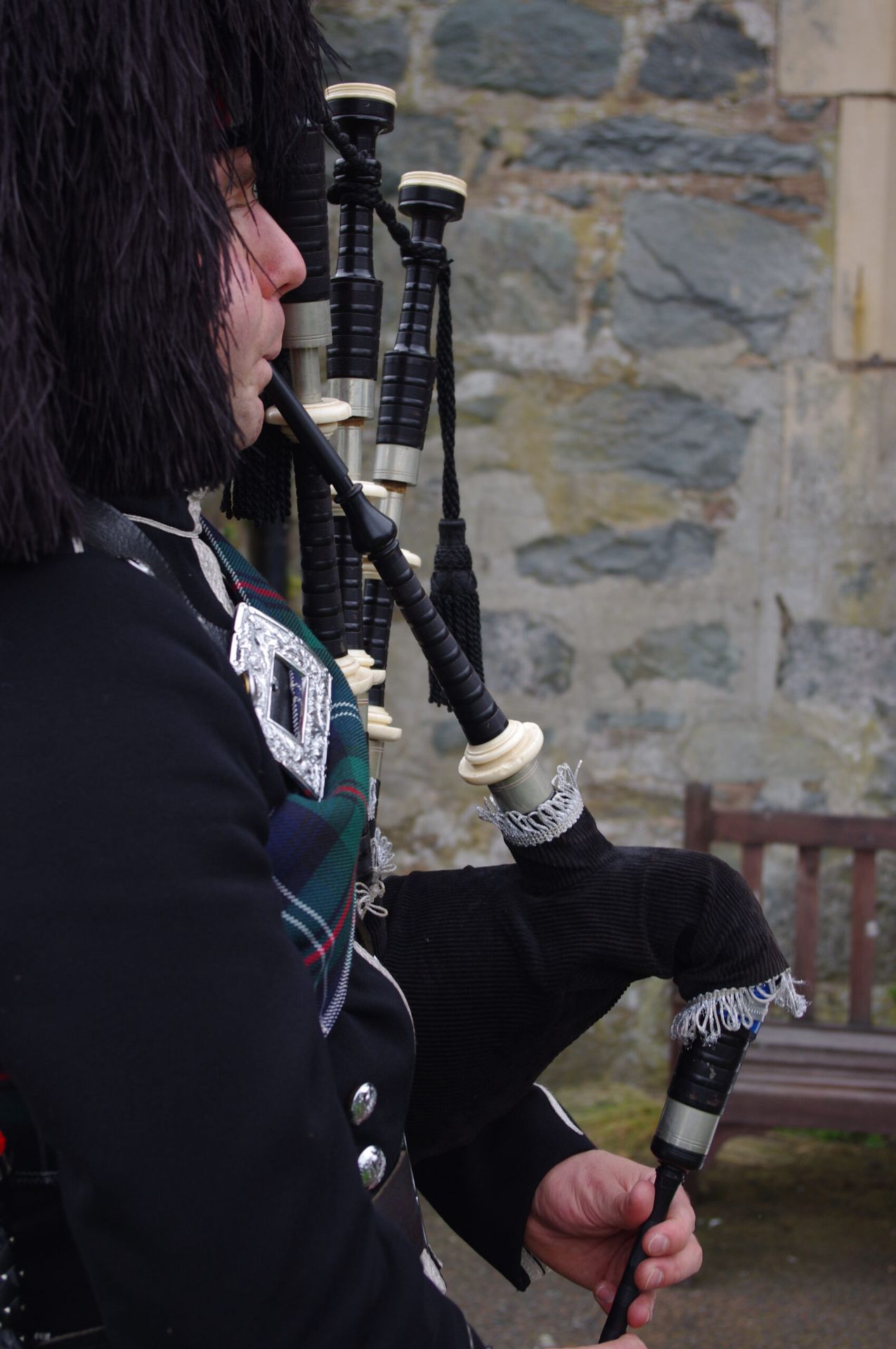 An image of a bagpiper in traditional highland garments playing his bagpipes