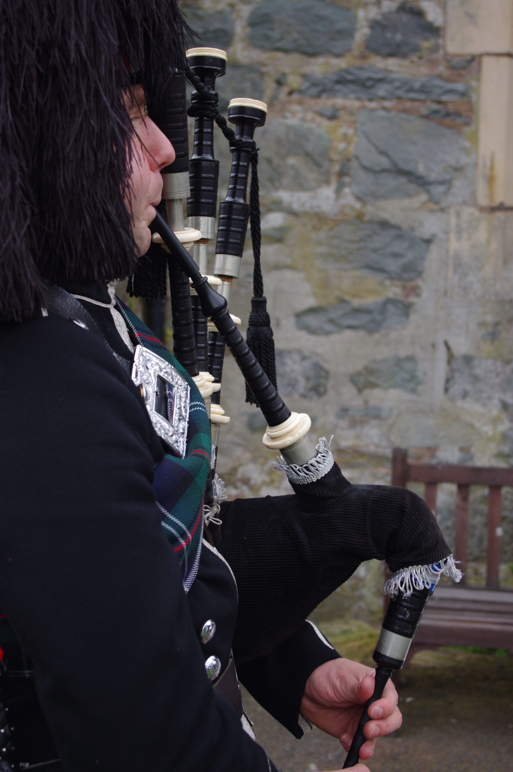 An image of a bagpiper in traditional highland garments playing his bagpipes